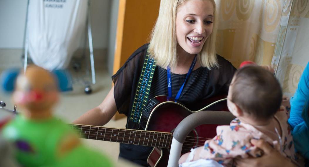 博彩平台网址大全 MA in Music Therapy student Kathleen Humphries works with young patient during field visit.